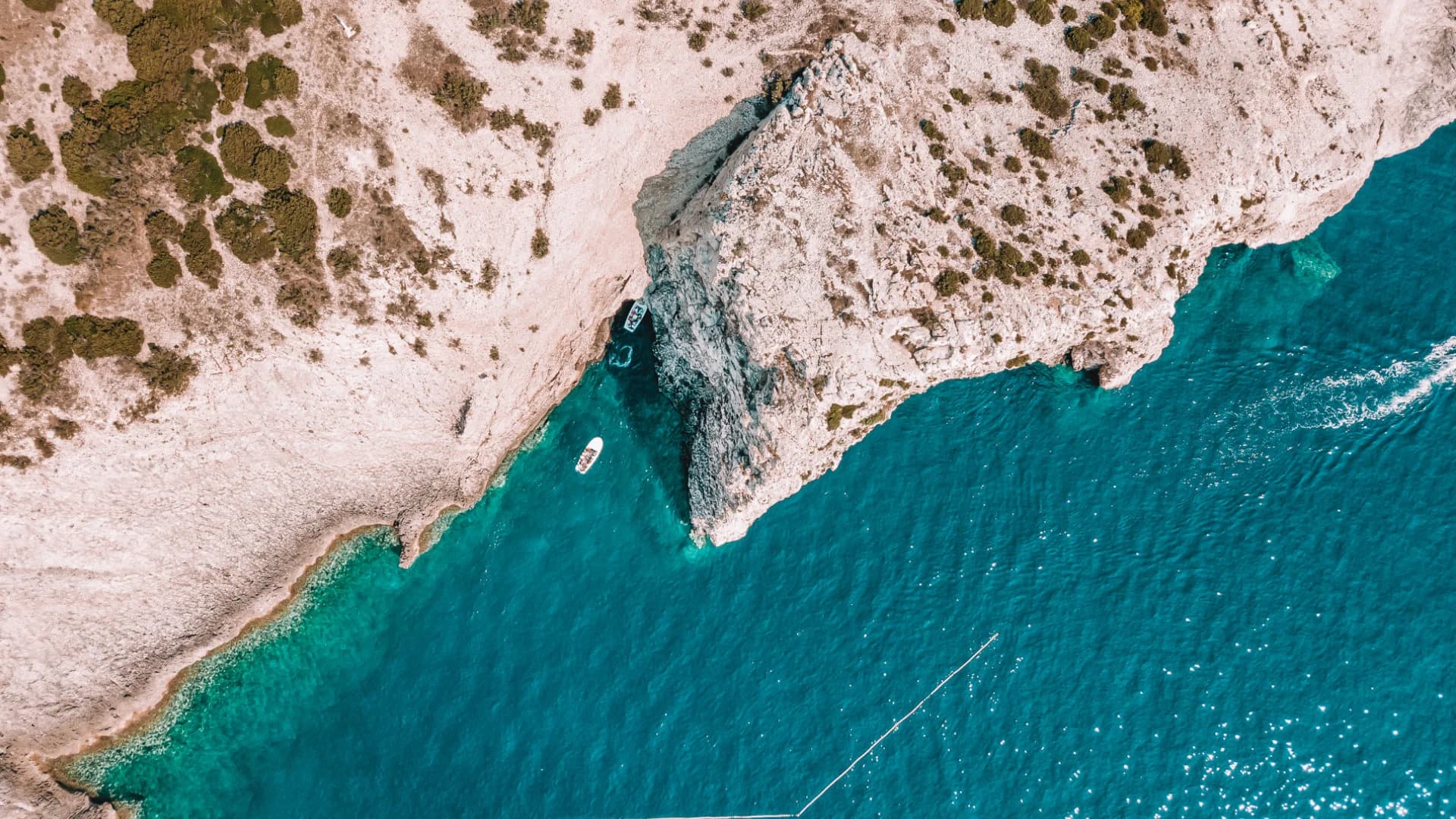 Boats waiting at the cliff entrance to the Blue Cave on Bisevo, seen from directly above